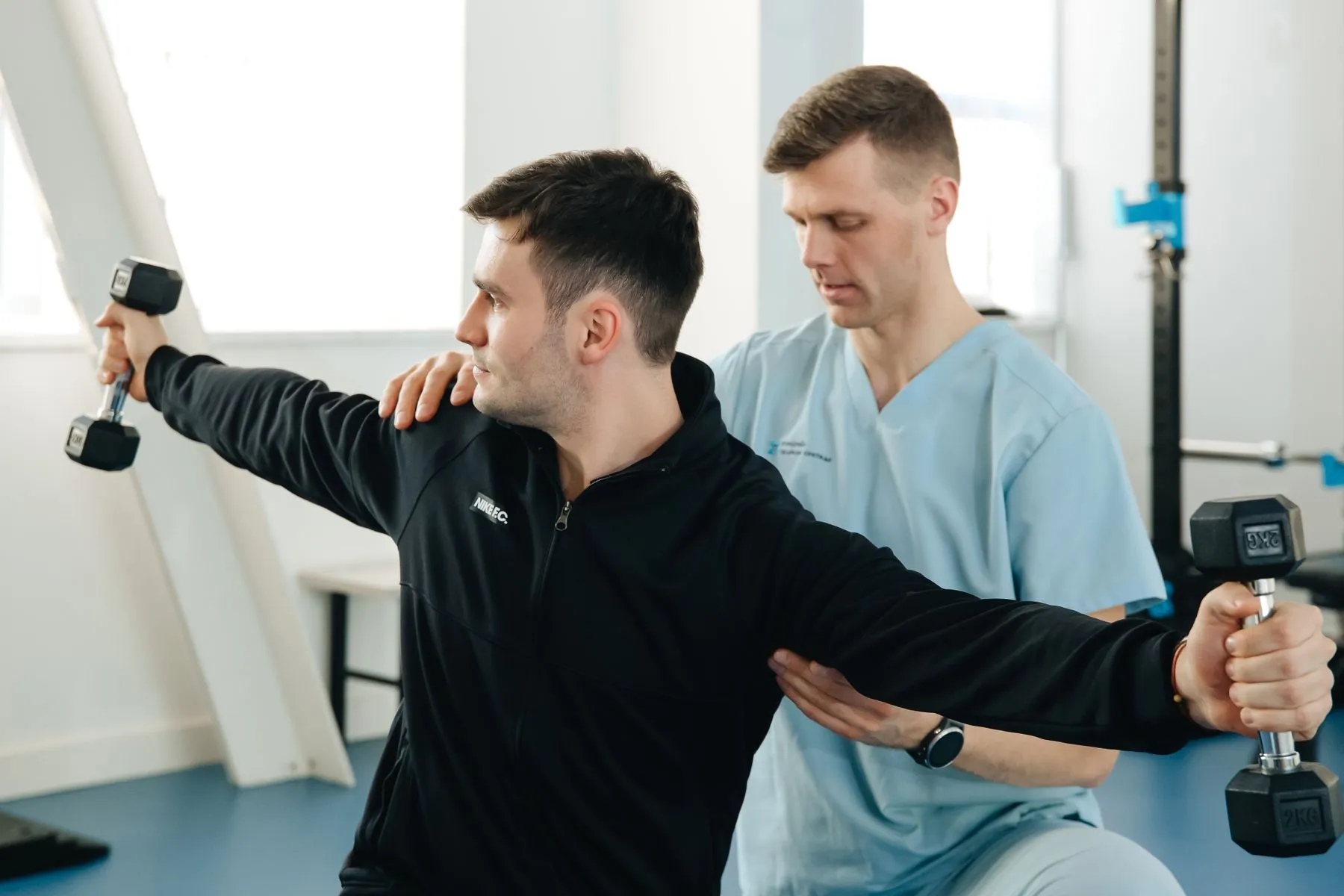 A physiotherapist guiding a patient's arm through a shoulder movement